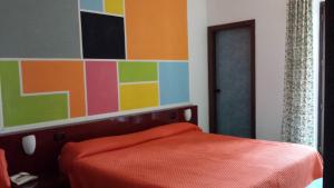 a bedroom with a orange bed and a colorful wall at Hotel Annabelle in Ischia