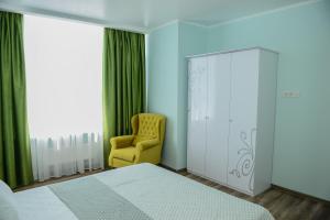 a bedroom with a bed and a yellow chair at Sea View Odessa in Odesa