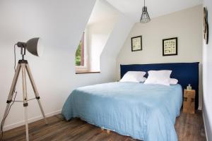 Un dormitorio con una cama azul y un trípode en Le moulin des Sens - SPA-SAUNA, en Orthez