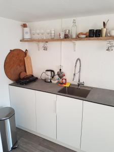 a kitchen with white cabinets and a sink at Unieke stadswoning voor 2 personen met Finse sauna in Apeldoorn