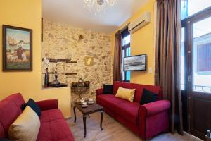 a living room with two red couches and a stone wall at Casa Di Silvia in Rethymno