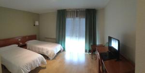a bedroom with a bed and a television at Hotel Arcea Villaviciosa in Villaviciosa