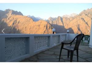 a chair on a balcony with a view of mountains at Ishwari Narayani Hotel in Joshīmath