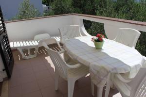 a white table and chairs with a table and flowers at Apartments Merica in Novalja