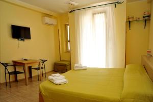 Schlafzimmer mit einem Bett, einem Tisch und einem Fenster in der Unterkunft Cala Dei Normanni - Camere sulle Mura in Otranto