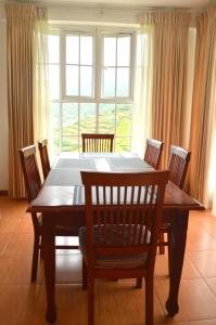 a dining room table with chairs and a large window at Villa Spring Acre in Nuwara Eliya