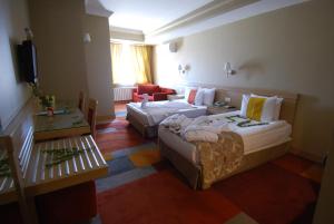 een hotelkamer met 2 bedden en een bank bij SV Business Hotel Diyarbakır in Diyarbakır