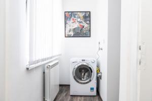 a washer and dryer in a white room with a picture at Modern Apartment in the Heart of the City Center! in Sarajevo