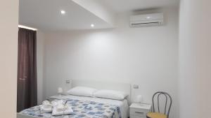 a white bedroom with a bed with shoes on it at B&B a casa di PaPi in Lizzano