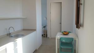 a kitchen with a sink and a table with a chair at Apartamentos Villa Primera in Cala Figuera
