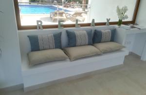 a white bench with pillows in a room with a window at Apartamentos Villa Primera in Cala Figuera
