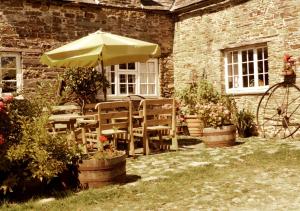 a table and chairs with an umbrella in front of a building at Old Newham Farm in Camelford