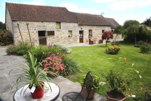 una casa con un patio con flores y plantas en Chambre d'hôte Courtoux en Saint-Denis-sur-Sarthon