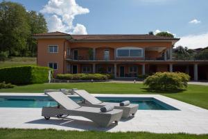 une maison avec deux chaises longues et une piscine dans l'établissement Calathea B&B, à Pettenasco