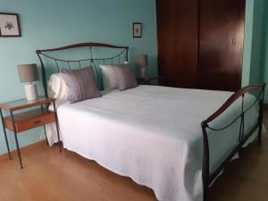 een slaapkamer met een groot bed met witte lakens en een tafel bij Dulce Vita Apartment in Praia