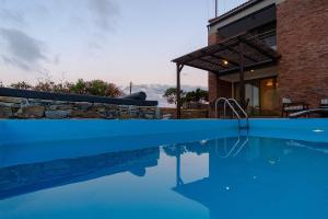 a swimming pool in front of a house at Gerakari Suites in Agia Pelagia