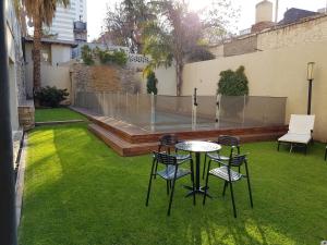 a patio with a table and chairs on the grass at Villaggio Hotel Boutique in Mendoza