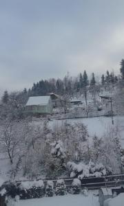 Ubytování u Krpců في Lhotka: ساحة مغطاة بالثلج مع منزل ومبنى