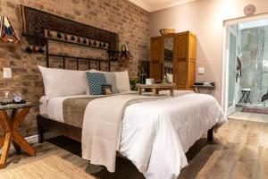 a bedroom with a large bed and a brick wall at Earthbound Guest House in Oudtshoorn