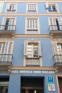 un bâtiment bleu avec des fenêtres blanches et un panneau sur celui-ci dans l'établissement Feel Hostels Soho Malaga, à Malaga