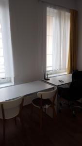 a white table and chairs in a room with windows at Bajta na obzidju in Maribor