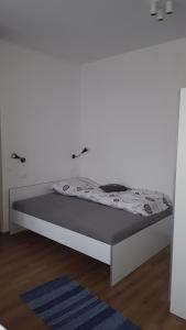 Bett in einem Zimmer mit einer weißen Wand in der Unterkunft Bajta na obzidju in Maribor