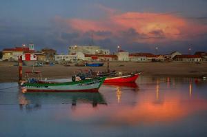 two boats sitting in the water with a town in the background at One step from the beach, praia da Aguda in Arcozelo