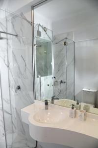 a white bathroom with a sink and a shower at Best of Athens Apartment in Athens