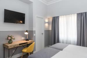 um quarto com uma cama e uma secretária com uma televisão em BYPILLOW Velázquez 45 em Madrid