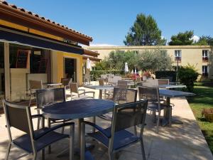 - un ensemble de tables et de chaises sur une terrasse dans l'établissement Logis Hôtel Restaurant Le Mas De L'Olivier, à Pont-Saint-Esprit