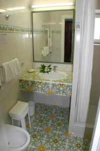 La salle de bains est pourvue d'un lavabo et d'un miroir. dans l'établissement Semiramis Hotel De Charme & Pools, à Ischia