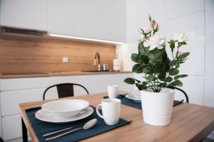 drewniany stół z dwoma talerzami i wazon z kwiatami w obiekcie Unique 3City Apartments - Grey Apartment w Gdańsku