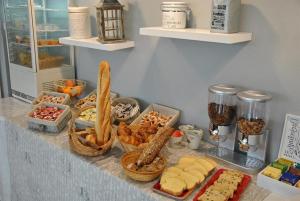 een buffet met brood en andere voedingsmiddelen op de toonbank bij Hôtel Angelic in Lourdes