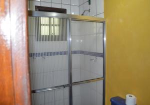y baño con cabina de ducha con puertas de cristal. en Pousada Wicca Vale, en São Bento do Sapucaí