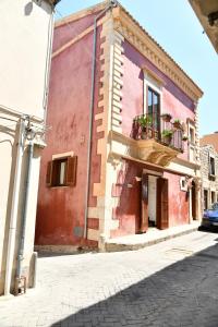 a pink building with a balcony on a street at Casa Vacanze Il RossAntico in Modica