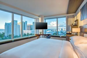 um quarto de hotel com uma cama grande e janelas em Hyatt Centric South Beach Miami em Miami Beach