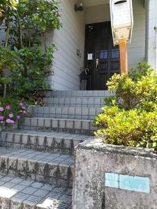 a front door of a house with stairs and flowers at Jukichi Owada Residence Twin Room in Sendai