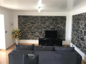 a living room with a couch and a stone wall at Vila do Rocha in Calheta