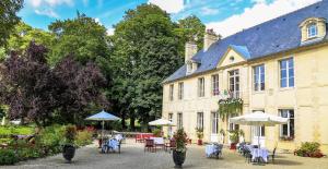 un bâtiment avec des tables, des chaises et des parasols dans l'établissement Château de Bellefontaine - Teritoria, à Bayeux