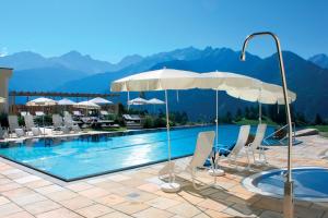 ein Swimmingpool mit Liegestühlen und Sonnenschirmen in einem Hotel in der Unterkunft Wellnessresidenz Schalber in Serfaus