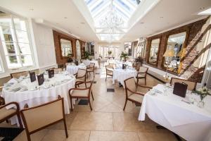 a restaurant with white tables and chairs and windows at Goldsborough Hall in Knaresborough