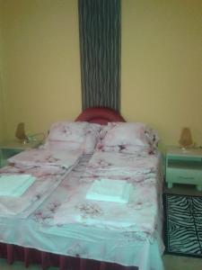 Una cama con sábanas rosas y una silla roja en una habitación. en József Apartman en Balatonmáriafürdő