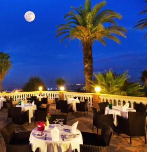 a restaurant with white tables and a palm tree at night at Grand Hotel Villa de France in Tangier