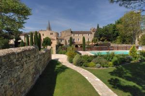 a stone wall in front of a house with a swimming pool at Hôtel Au Logis des Remparts in Saint-Émilion
