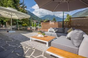 a patio with a couch and a table and an umbrella at Gasthof Restaurant Waldcafé in Mayrhofen