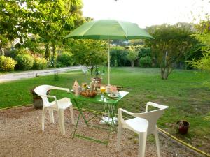 uma mesa com um guarda-sol verde e duas cadeiras em Chez Mamouska em Cassis