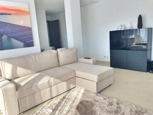 een woonkamer met een witte bank en een schilderij bij Cavalo Preto Luxury Beach Resort - C201 in Quarteira