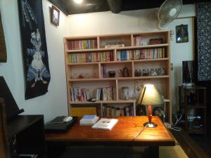 a desk with a lamp and a book shelf with books at 艸風舎 Soufusha in Arita