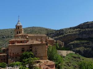 an old building with a tower on a mountain at Hotel Posada del Adarve in Albarrac&iacute;n