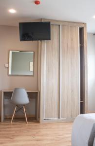 Schlafzimmer mit Holzschränken, einem Stuhl und einem Spiegel in der Unterkunft O Vendaval Hostal Restaurante in Barreiros